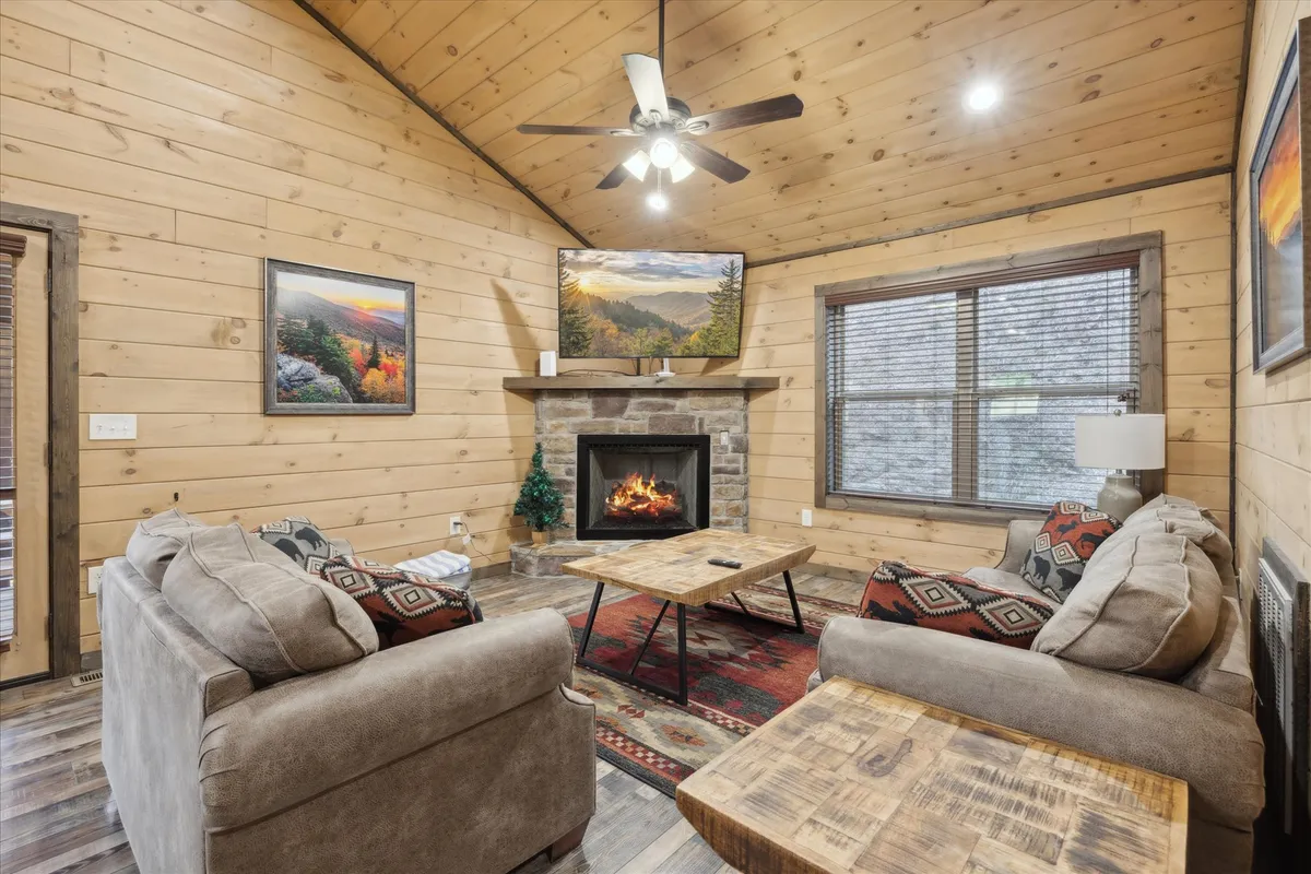 A welcoming living room scene featuring a glowing fireplace, a comfortable sofa, a coffee table, and tasteful artwork. Large windows hint at views of the outdoors, while the overall mood is warm and inviting—perfect for quiet nights in after a day of adventure.