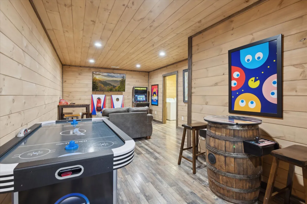 A vibrant game room scene with an air hockey table, colorful wall art, comfortable seating, and multiple arcade machines. The mood is energetic and fun, ideal for family game nights or friendly competitions among friends.