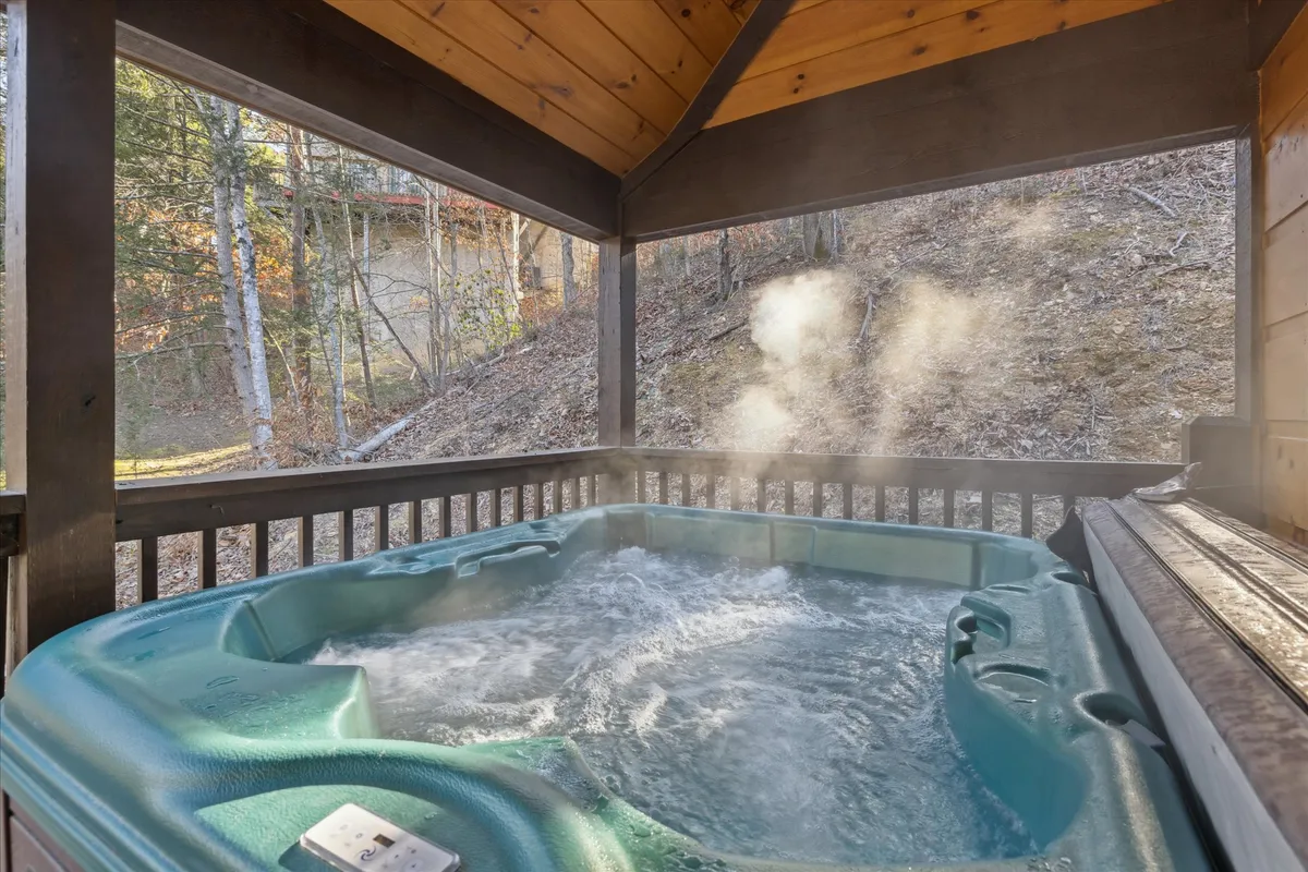 An inviting hot tub nestled under a wooden structure, with steam rising in the cool mountain air. The scene exudes tranquility and offers a glimpse of the surrounding natural landscape, suggesting a romantic and soothing retreat.