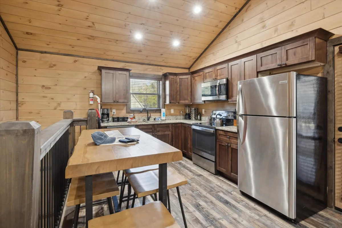 A warm and welcoming kitchen featuring a spacious kitchen island, stainless steel appliances, and wooden cabinetry. The layout is open, inviting, and perfectly suited to both cooking and gathering, with ample workspace and a cozy atmosphere.