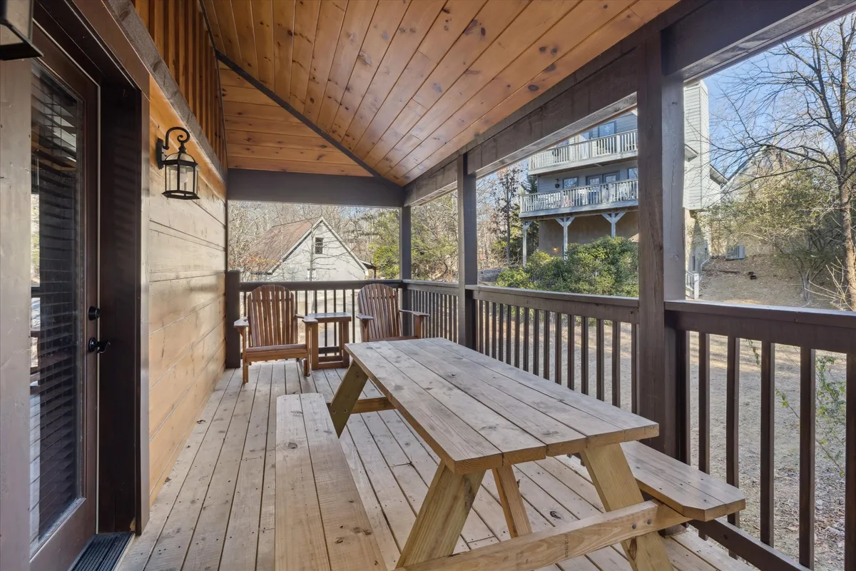 An inviting outdoor space with a wooden picnic table, rocking chairs, and a wooden railing overlooking the natural surroundings. The scene evokes moments of outdoor dining, relaxation, and meaningful conversations while immersed in nature.